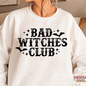 May include: White sweatshirt with the text "BAD WITCHES CLUB" in black, decorated with bats and stars. A casual, comfortable top for Halloween or everyday wear.