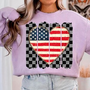 May include: A lavender sweatshirt with a distressed checkered design and a heart-shaped American flag graphic.