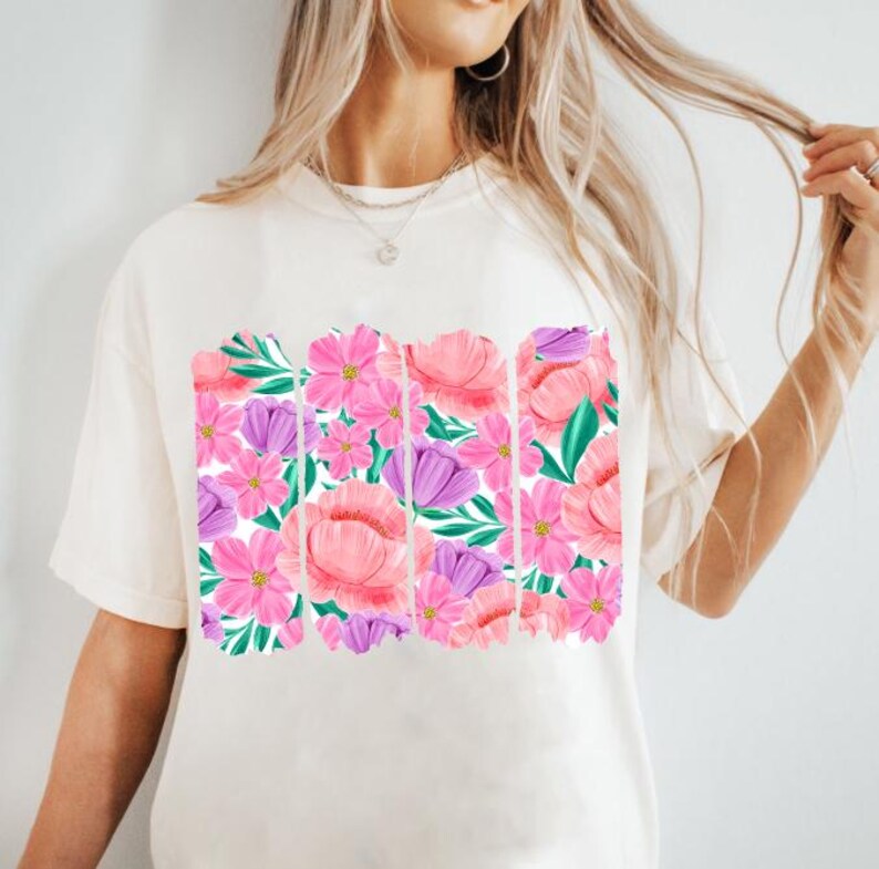 May include: A white t-shirt with a floral print design. The print features pink, purple, and green flowers.
