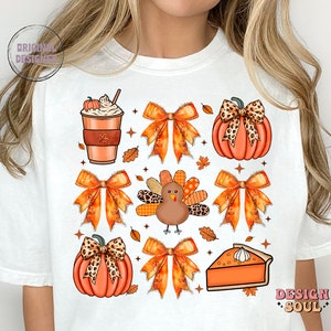 May include: White t-shirt with a Thanksgiving-themed design featuring a pumpkin, a turkey, a pie, a coffee cup, and bows with a leopard print pattern.