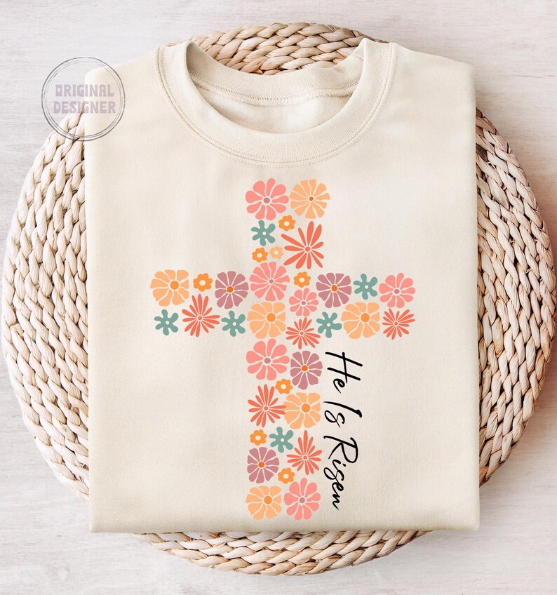 May include: A cream-colored sweatshirt with a floral cross design and the text "He is Risen".