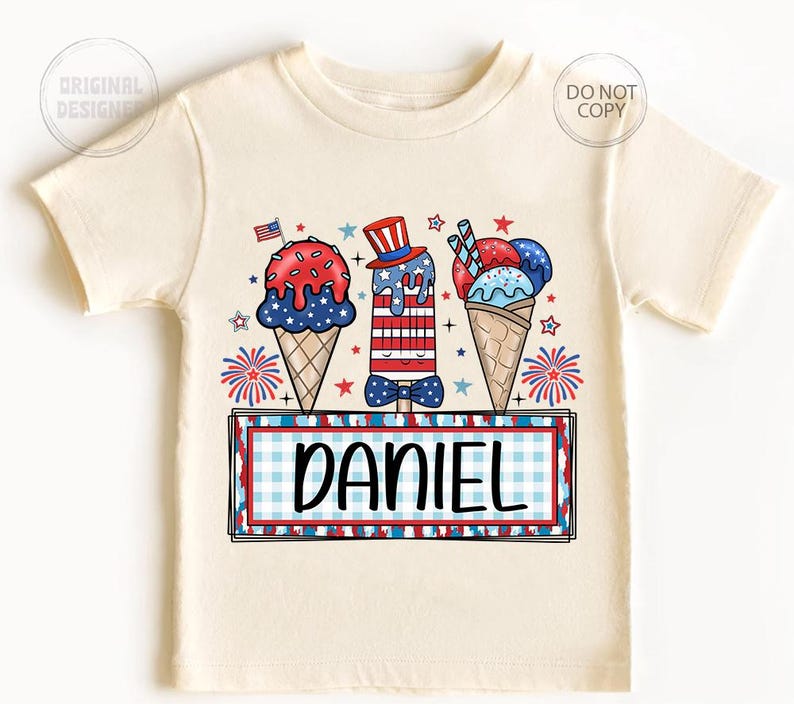 May include: Cream-colored t-shirt featuring a patriotic ice cream design with red, white, and blue colors. The design includes ice cream cones and popsicles, a small American flag, and the name "DANIEL" in a rectangular frame.