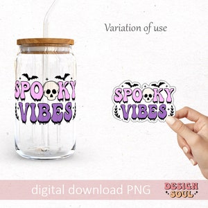 May include: A purple and pink sticker with the text "Spooky Vibes" and a skull graphic. The sticker is on a white background and is being held by a hand.