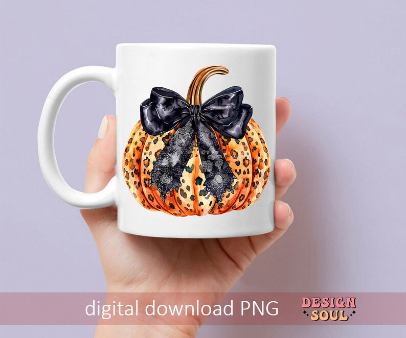 May include: A white ceramic mug with a black and orange leopard print pumpkin with a black bow. The pumpkin is centered on the mug.