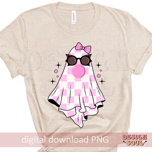 May include: A beige t-shirt with a pink and white checkered ghost wearing black sunglasses and a pink bow. The ghost has a pink bubble coming out of its mouth. The text "digital download PNG" is at the bottom of the shirt.