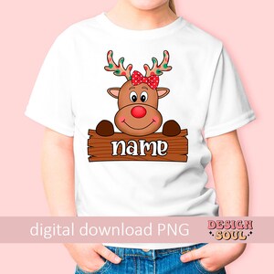 Peut inclure: T-shirt blanc avec un renne de dessin anim&eacute; portant un n&oelig;ud rouge. Le renne regarde par-dessus une pancarte en bois qui dit "name".