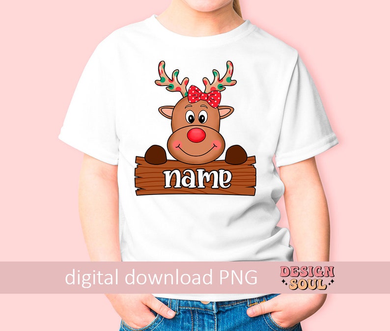 Peut inclure: T-shirt blanc avec un renne de dessin anim&eacute; portant un n&oelig;ud rouge. Le renne regarde par-dessus une pancarte en bois qui dit "name".