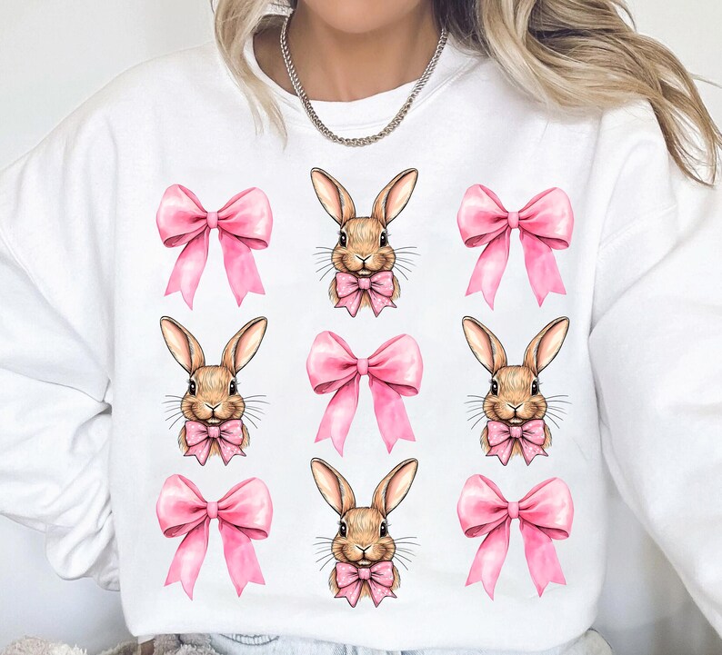 May include: White sweatshirt with a repeated pattern of pink bows and brown bunnies wearing pink bows.
