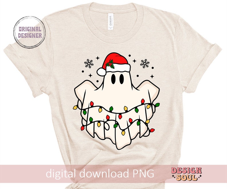May include: A white ghost wearing a red Santa hat with green holly and a string of colorful Christmas lights around it. The ghost is on a beige t-shirt.