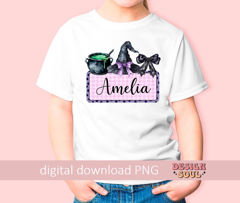 May include: A white t-shirt with a pink and white checkered design with black polka dots. The design features a witch's hat, a cauldron, and the name "Amelia".