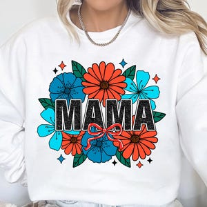 Pu&ograve; includere: Felpa bianca con un design floreale e la parola "MAMA" in lettere nere. I fiori sono rossi, blu e verdi.