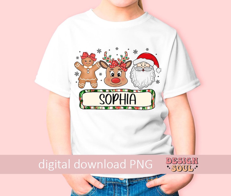 May include: White t-shirt with a Christmas design featuring a gingerbread person, a reindeer, and Santa Claus. The design includes the name "Sophia" in a green and red plaid banner.