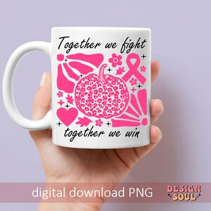 Peut inclure: Une tasse en c&eacute;ramique blanche avec un motif rose et noir. Le motif repr&eacute;sente une citrouille &agrave; imprim&eacute; l&eacute;opard, un ruban rose et le texte "Ensemble nous luttons, ensemble nous gagnons".