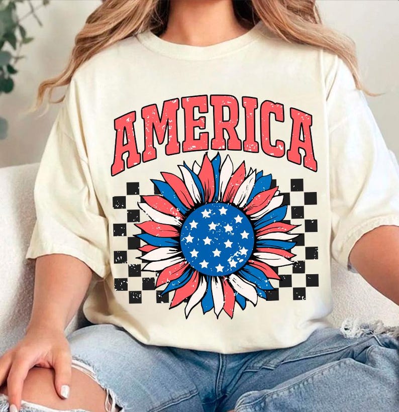 May include: A white t-shirt with a red, white, and blue sunflower graphic and the word "AMERICA" in red letters. The sunflower has a blue center with white stars.