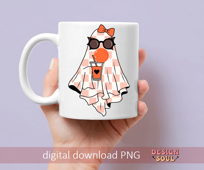 May include: White ceramic mug with a pink and white checkered ghost wearing sunglasses and holding a glass of orange juice. The ghost has a pink bow on its head. The mug has the text "Design Soul" on the bottom.