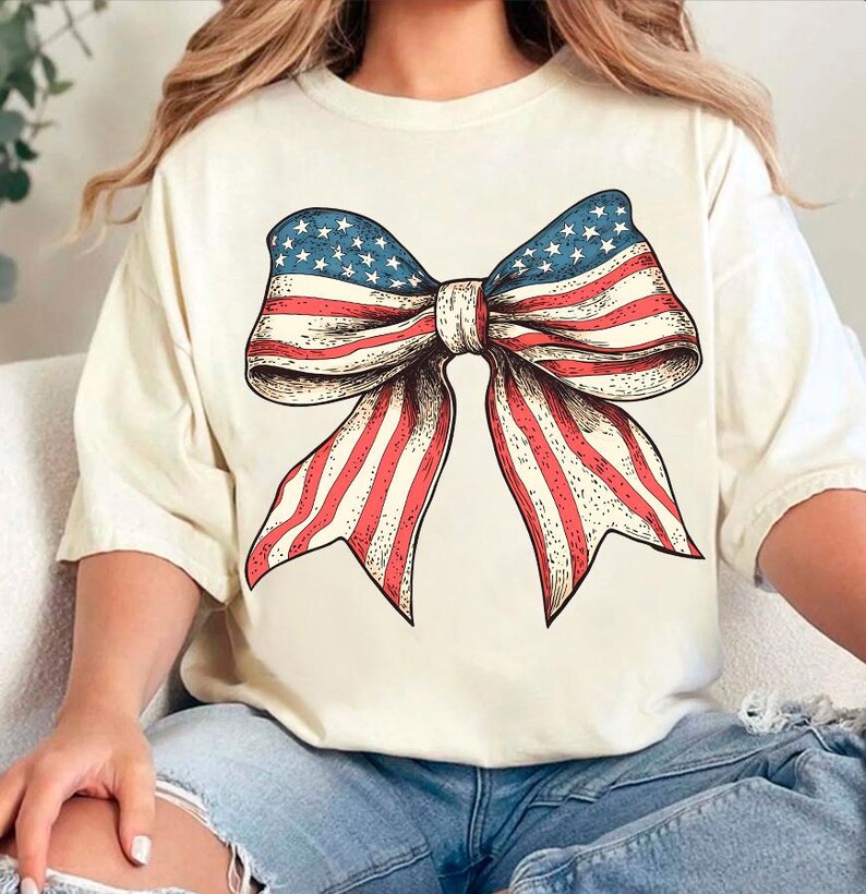Peut inclure: Un t-shirt blanc avec un n&oelig;ud rouge, blanc et bleu fait d'un imprim&eacute; de drapeau am&eacute;ricain.