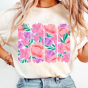 May include: A white t-shirt with a floral print design. The print features pink, purple, and green flowers and leaves.