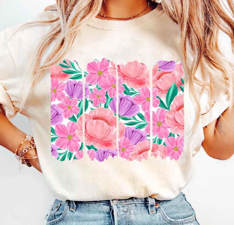 May include: A white t-shirt with a floral print design. The print features pink, purple, and green flowers and leaves.