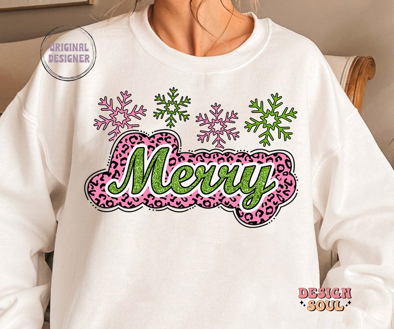 May include: White sweatshirt featuring a green and pink "Merry" graphic with a leopard print design. The graphic is surrounded by four snowflakes, two green and two pink.