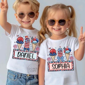 May include: Two children wearing white t-shirts with patriotic ice cream cone designs. The shirts feature red, white, and blue ice cream cones, fireworks, and the names "DANIEL" and "SOPHIA" in a framed design. Both children are wearing sunglasses.