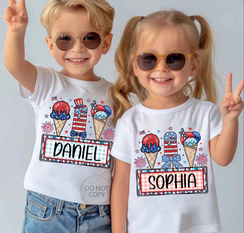 May include: Two children wearing white t-shirts with patriotic ice cream cone designs. The shirts feature red, white, and blue ice cream cones, fireworks, and the names "DANIEL" and "SOPHIA" in a framed design. Both children are wearing sunglasses.