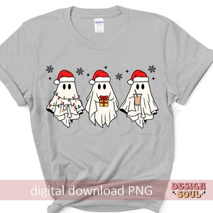 May include: A gray t-shirt with a design of three ghosts wearing Santa hats. The ghosts are holding a gift, a cup of coffee, and Christmas lights.