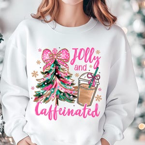 May include: White sweatshirt with a pink and green Christmas tree, a pink bow, and a cup of coffee. The text "Jolly and Caffeinated" is written in pink.