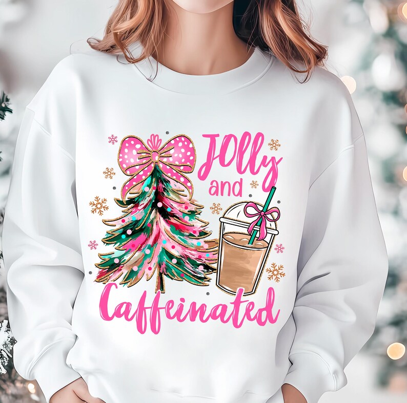 May include: White sweatshirt with a pink and green Christmas tree, a pink bow, and a cup of coffee. The text "Jolly and Caffeinated" is written in pink.