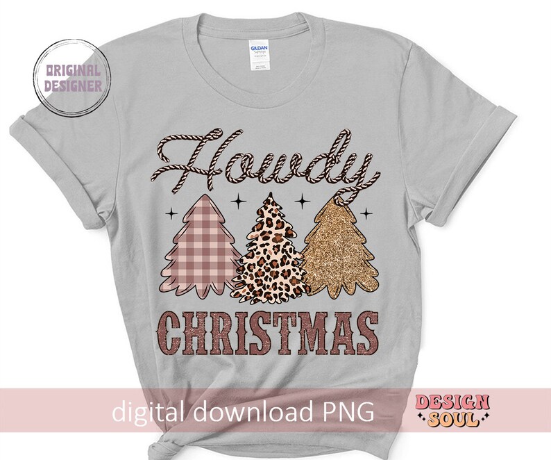 May include: A gray t-shirt with the text "Howdy Christmas" in a brown rope-like font. Three Christmas trees are depicted in the center of the shirt. The trees are pink and white plaid, leopard print, and gold glitter.