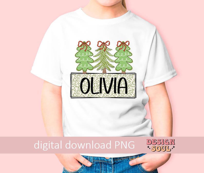 May include: White t-shirt with a design of three green Christmas trees with red bows and the name "Olivia" in a black and white leopard print box.