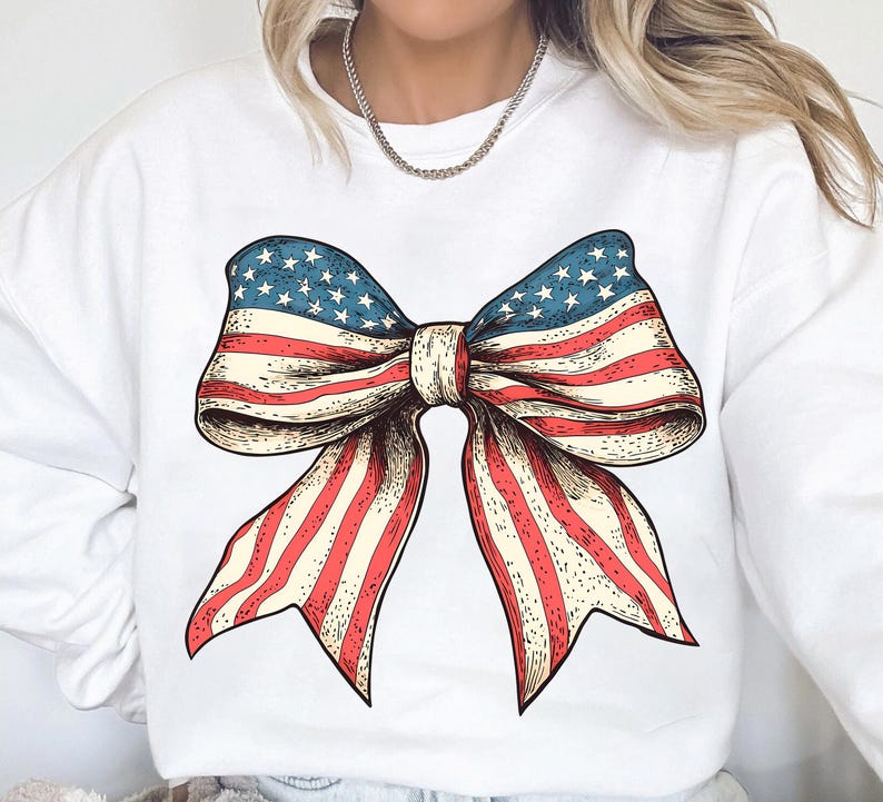 Peut inclure: Sweat-shirt blanc avec un graphique de n&oelig;ud rouge, blanc et bleu. Le n&oelig;ud est dessin&eacute; dans un style vintage et ressemble au drapeau am&eacute;ricain.