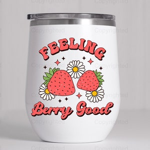 May include: White stainless steel tumbler with a red and green graphic of strawberries and flowers. The text "Feeling Berry Good" is printed in red on the tumbler.