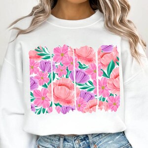 May include: White sweatshirt with a floral print design. The print features pink, purple, and green flowers.