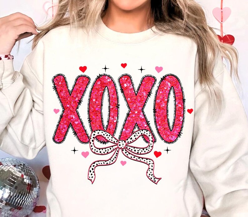 May include: White sweatshirt with a pink glitter XOXO design and a black and white polka dot bow.