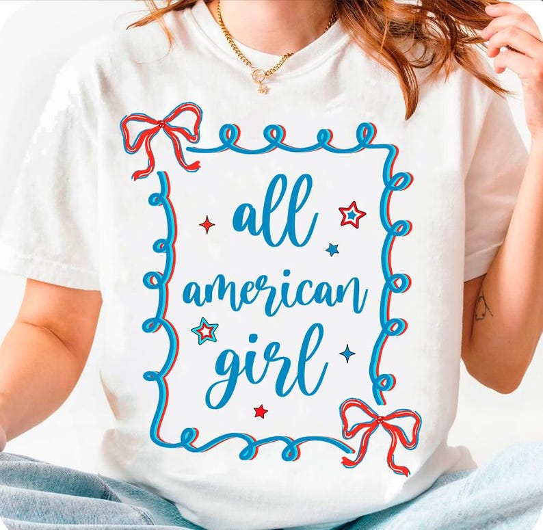Peut inclure: T-shirt blanc avec un motif graphique bleu et rouge. Le graphique pr&eacute;sente un n&oelig;ud rouge et bleu, des &eacute;toiles et le texte "all american girl".