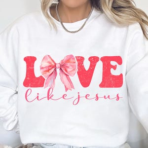 May include: White sweatshirt with a pink bow and the words "LOVE like jesus" in red.