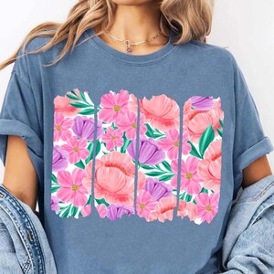 May include: A blue t-shirt with a floral print design. The print features pink, purple, and green flowers in a repeating pattern.