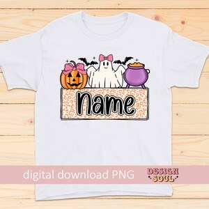 May include: A white t-shirt with a Halloween-themed design featuring a ghost, a pumpkin, and a cauldron. The design is on a leopard print background with the word "name" in black text.