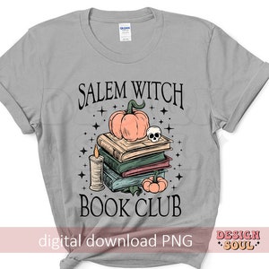 Op de afbeelding: Een grijs T-shirt met de tekst "Salem Witch Book Club" in zwart. In het midden van het shirt is een stapel boeken met een pompoen en een schedel erop afgebeeld.