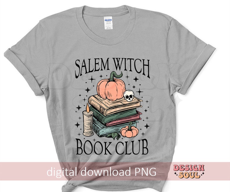 Op de afbeelding: Een grijs T-shirt met de tekst "Salem Witch Book Club" in zwart. In het midden van het shirt is een stapel boeken met een pompoen en een schedel erop afgebeeld.