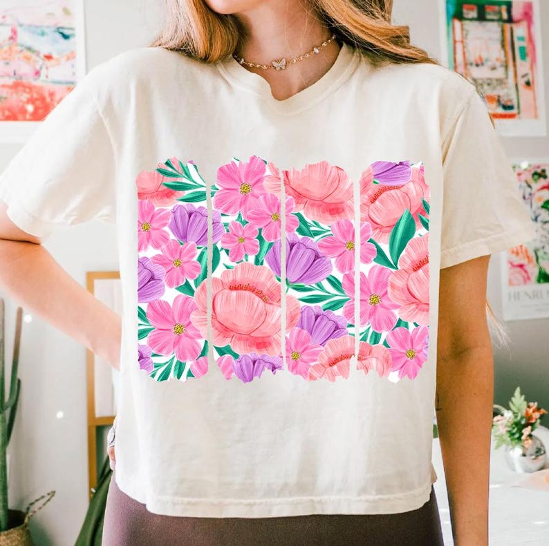 May include: A white t-shirt with a floral print featuring pink and purple flowers with green leaves.