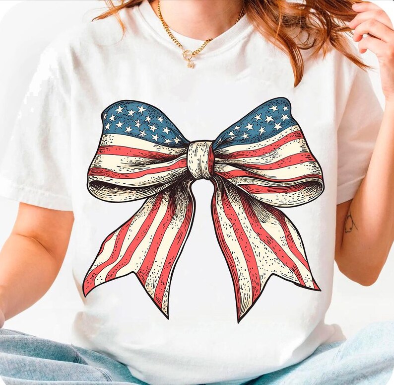Peut inclure: T-shirt blanc avec un n&oelig;ud rouge, blanc et bleu imprim&eacute; sur le devant. Le n&oelig;ud est dessin&eacute; dans un style vintage et ressemble au drapeau am&eacute;ricain.