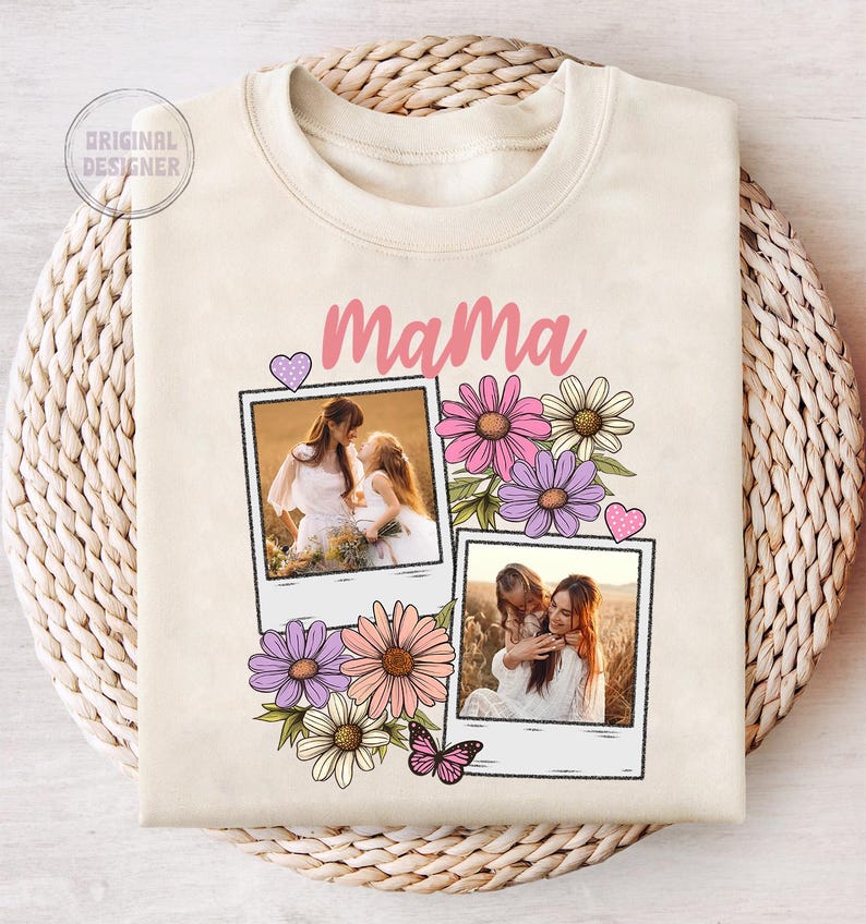 May include: Cream-colored sweatshirt with the word "Mama" in pink script. The design includes two polaroid-style photo frames with images of a mother and child, surrounded by colorful flowers and a butterfly.