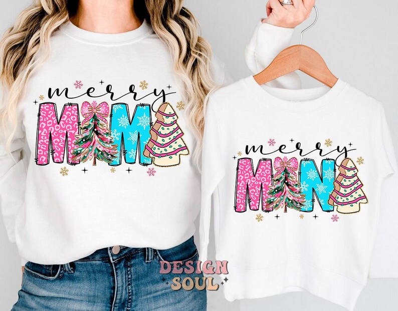 Peut inclure: Chemise &agrave; manches longues blanches avec un motif sur le th&egrave;me de No&euml;l. Les chemises pr&eacute;sentent le texte "merry" et "mama" avec des sapins de No&euml;l roses, bleus et verts.