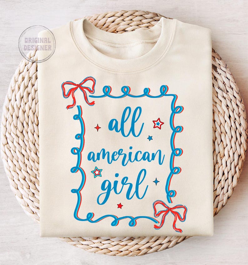 Peut inclure: Un sweat-shirt cr&egrave;me avec un motif rouge, blanc et bleu. Le motif pr&eacute;sente un cadre avec un n&oelig;ud en haut et en bas, et le texte "all american girl" &agrave; l'int&eacute;rieur du cadre.