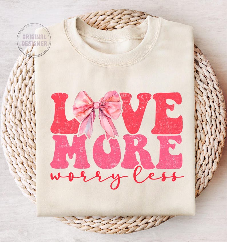 May include: A cream-colored sweatshirt with a pink bow and the text "LOVE MORE worry less" in a pink distressed font.