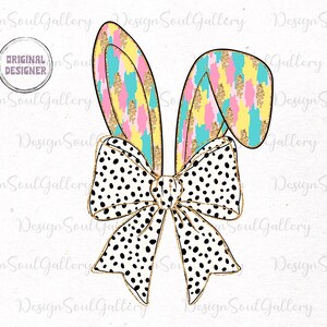 May include: A white bow with black polka dots and gold accents, topped with two pastel bunny ears with gold glitter. The ears are pink, yellow, and blue with a white and blue abstract pattern.