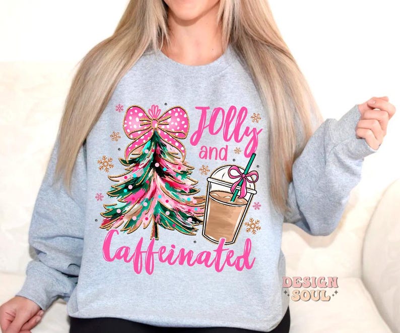 May include: A gray sweatshirt with a pink and green Christmas tree, a pink bow, and a cup of coffee. The text "Jolly and Caffeinated" is printed on the sweatshirt.