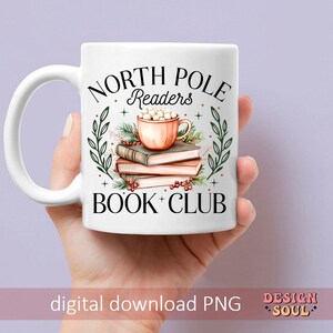 May include: White ceramic mug with a black and white design that says "North Pole Readers Book Club". The mug has a green and red holly design with a cup of hot chocolate with marshmallows on top of a stack of books.