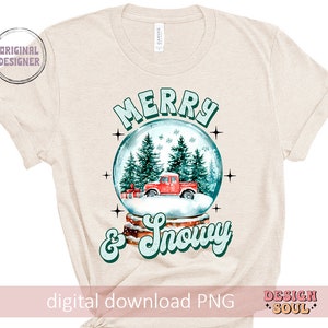 May include: A beige t-shirt featuring a snow globe design with a red truck, green trees, and white snow. The text "Merry & Snowy" is written in a retro font.